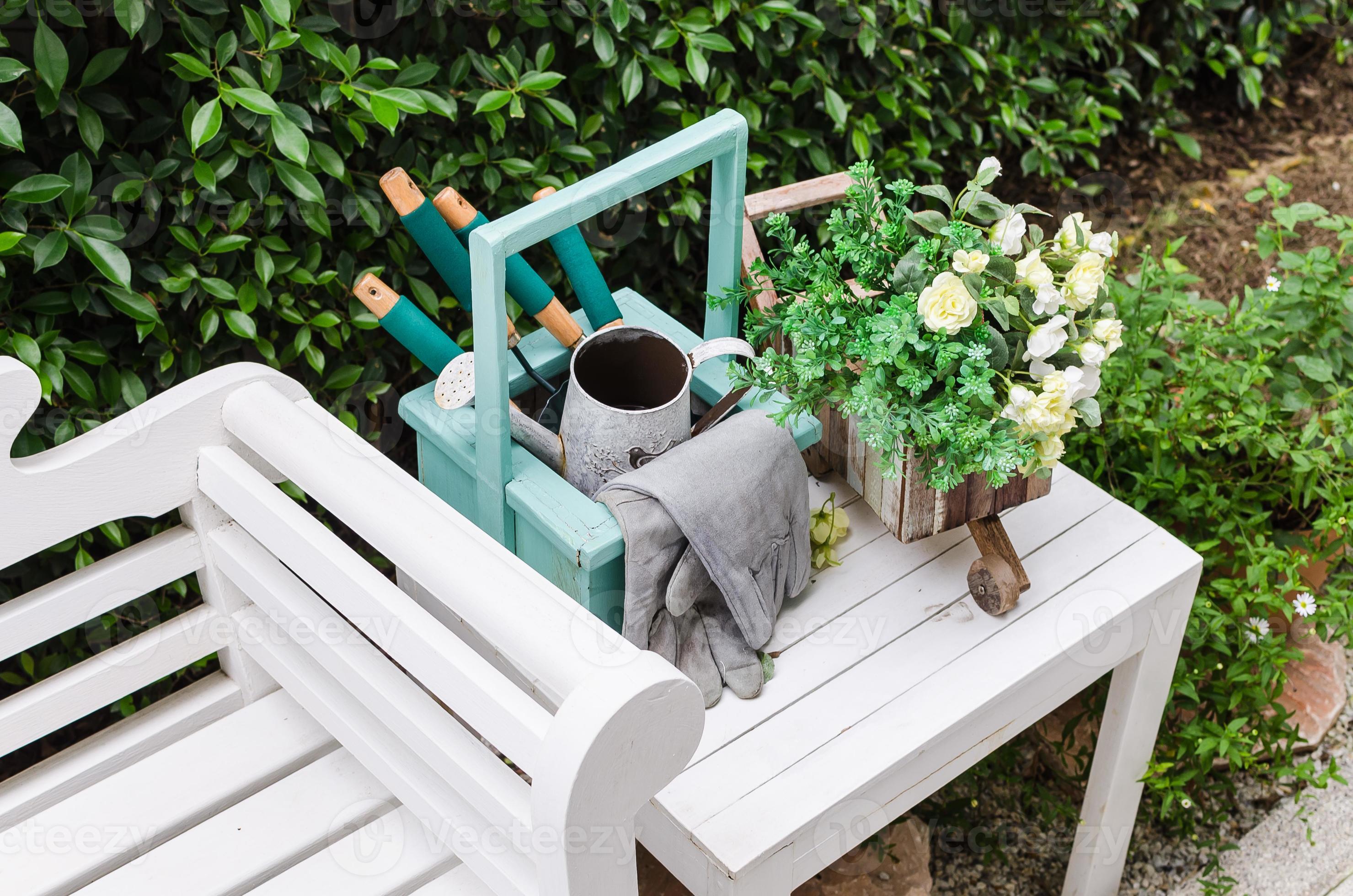 ferramentas de jardinagem na mesa e no banco de madeira branca foto