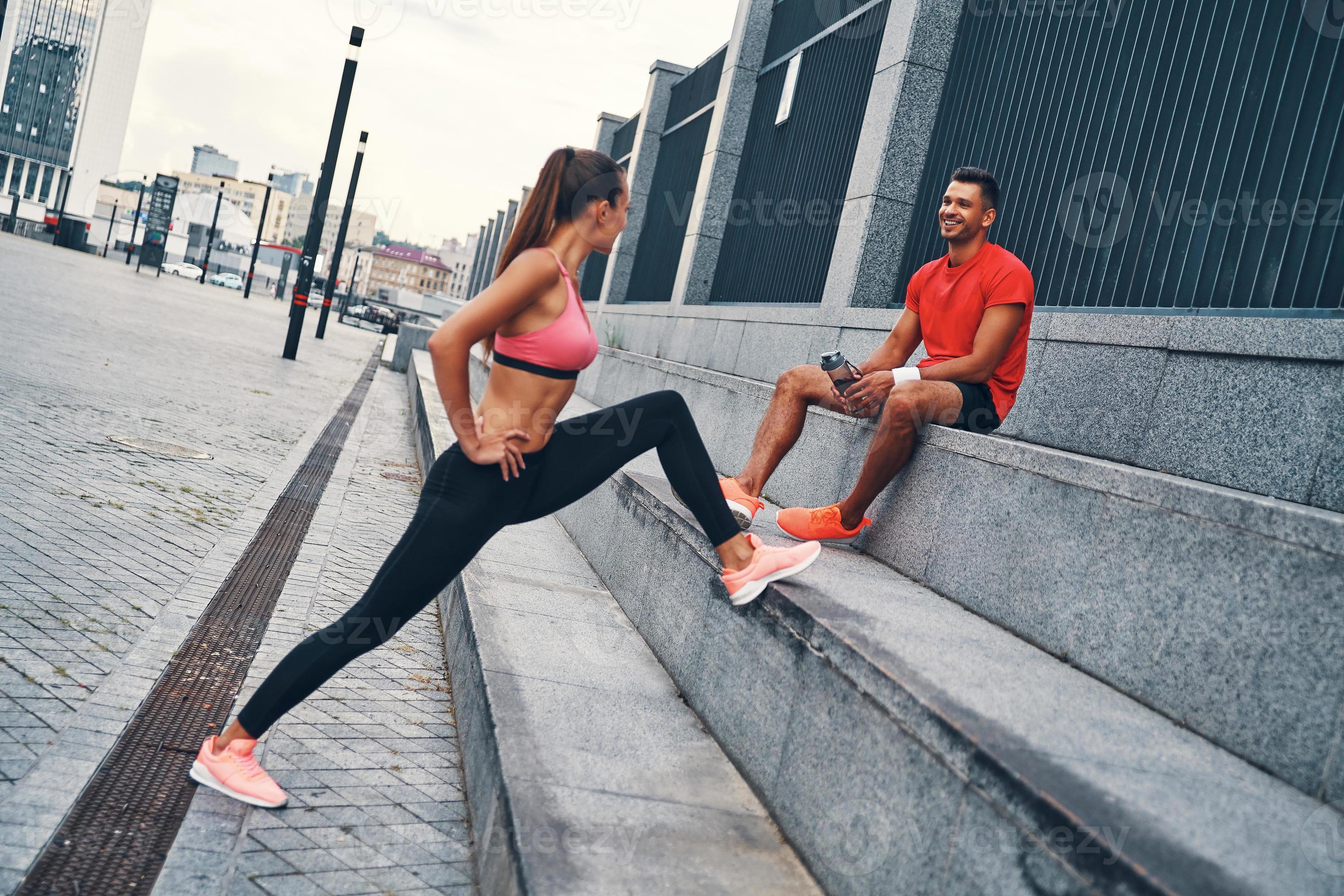 lindo casal jovem em roupas esportivas aquecendo e esticando