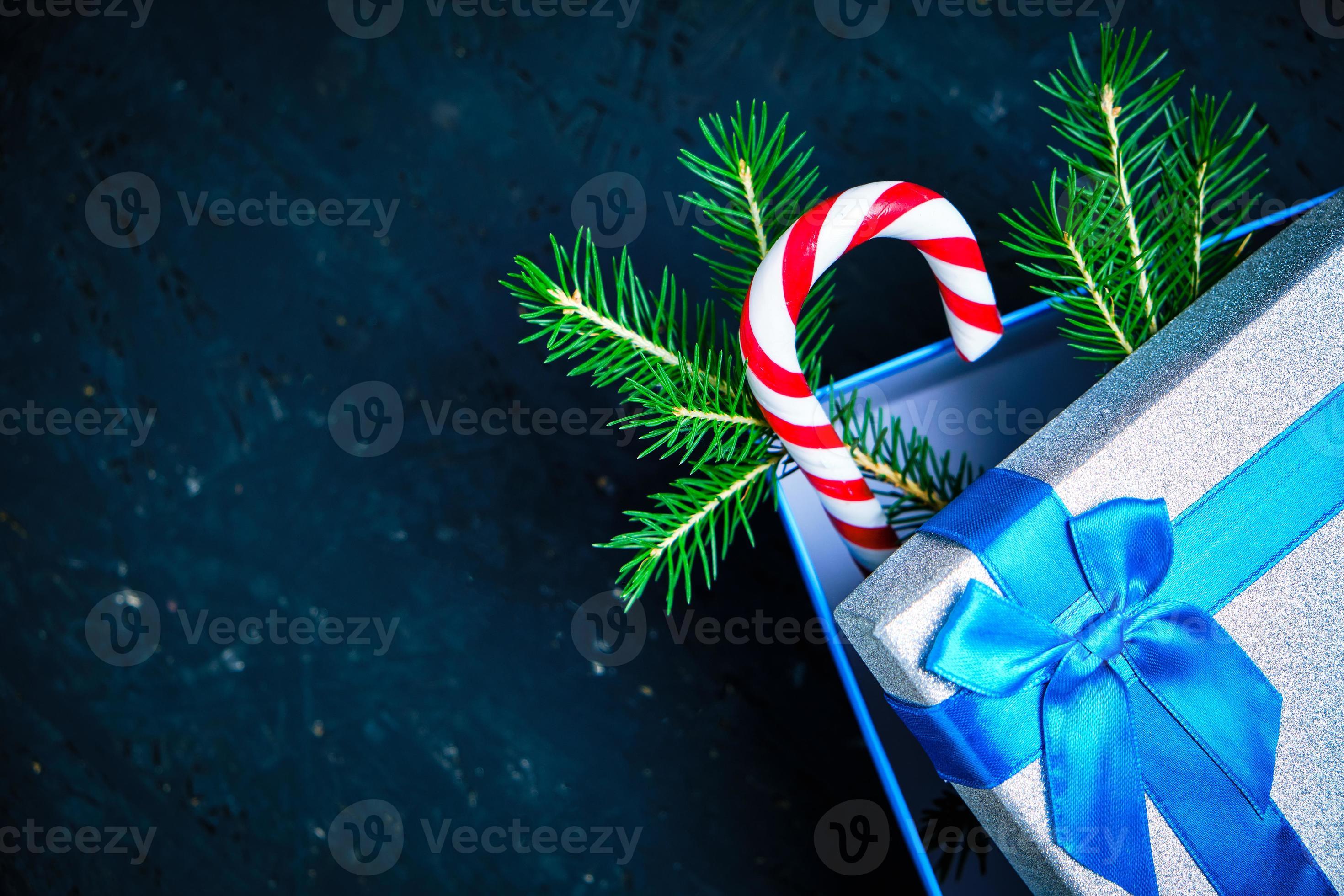 caixa de presente de natal amarrada com fita azul com laço com árvore de  natal verde e caramelo em fundo escuro. 16277563 Foto de stock no Vecteezy