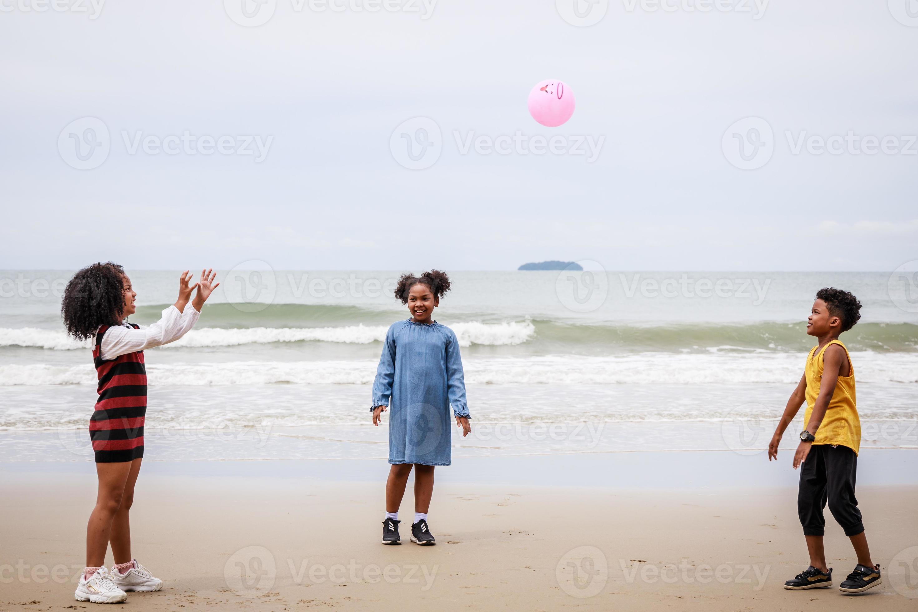 Imagem de crianças jogando bola na beira da praia.