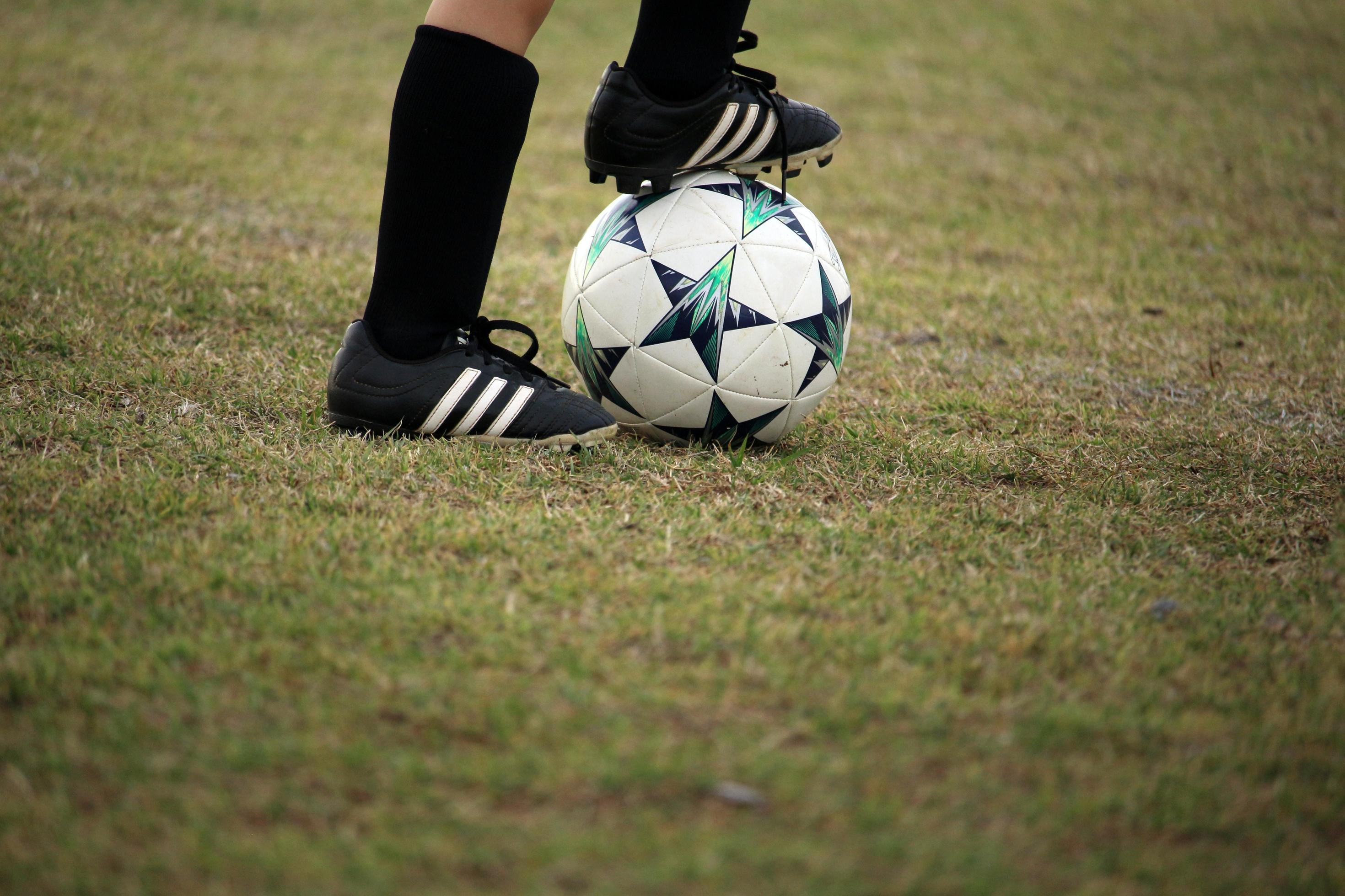 Pés Em Tênis E Bola De Futebol Ao Sol. Jogo Infantil. Foto de Stock -  Imagem de esfera, pés: 192406154