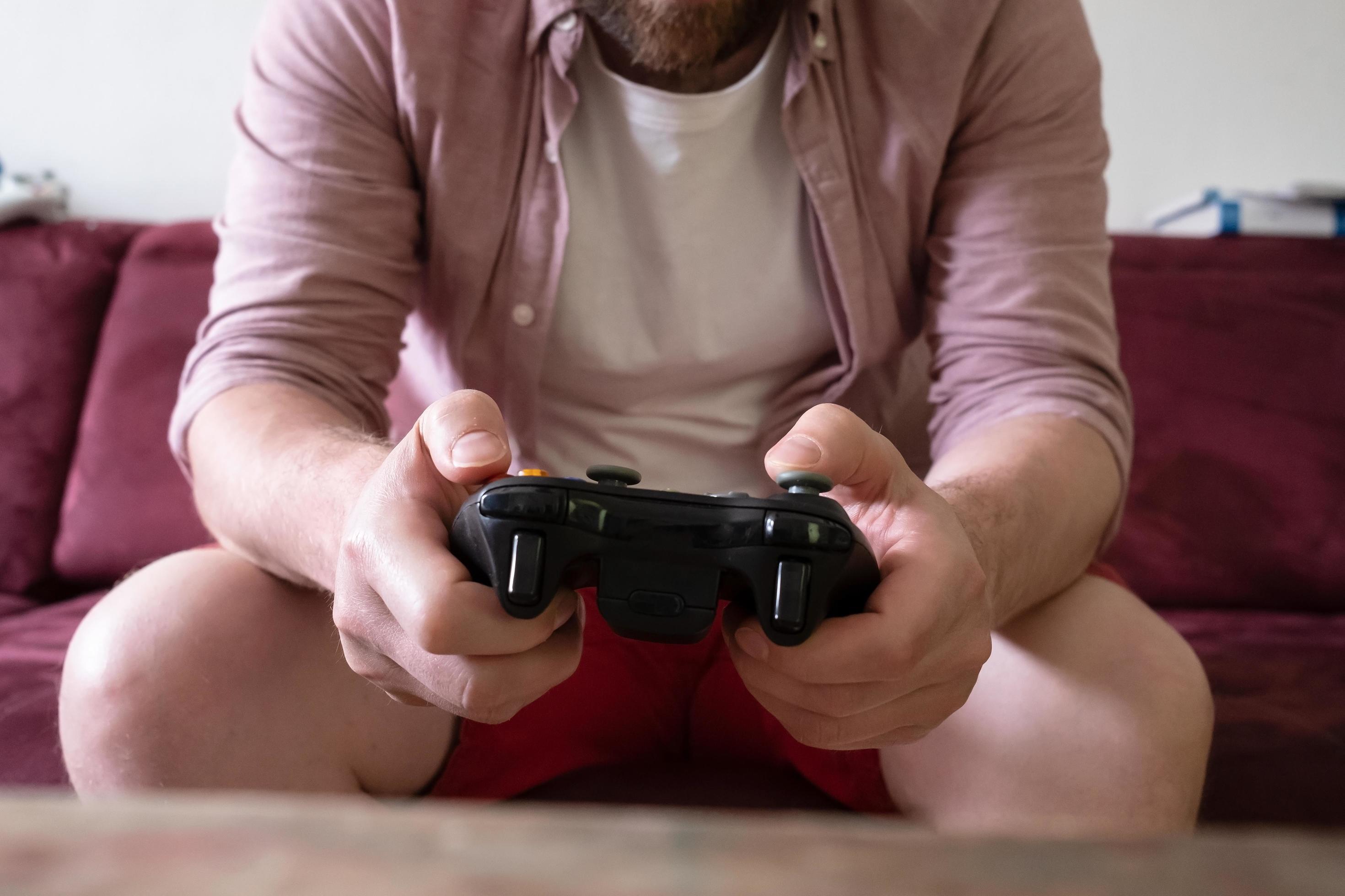 Jogador jogando videogame de console de tiro em primeira pessoa na tv  enquanto a namorada está comendo pipoca e dando-lhe conselhos sentado no  sofá. casal no sofá desfrutando de simulação de jogos