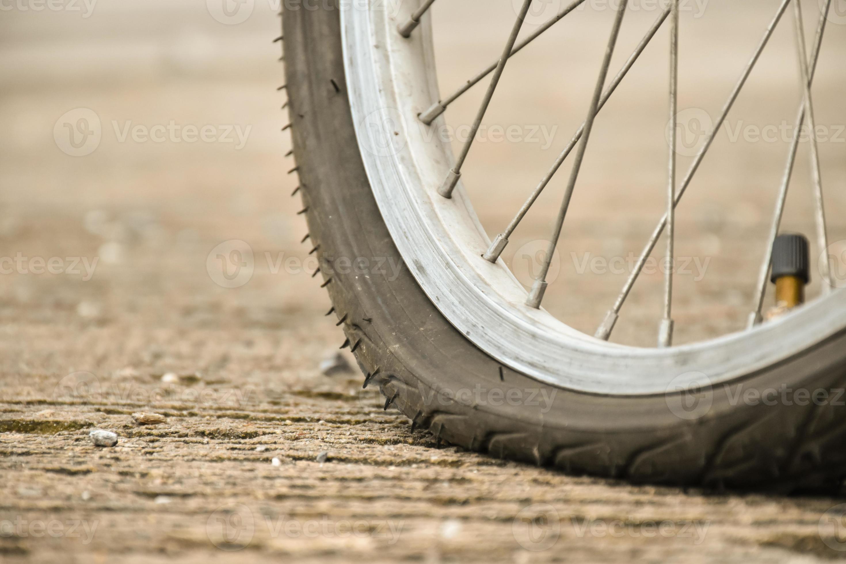 visão aproximada da roda furada da bicicleta ou do pneu furado da bicicleta  que estacionou na estrada e esperando para consertar. 18952047 Foto de  stock no Vecteezy