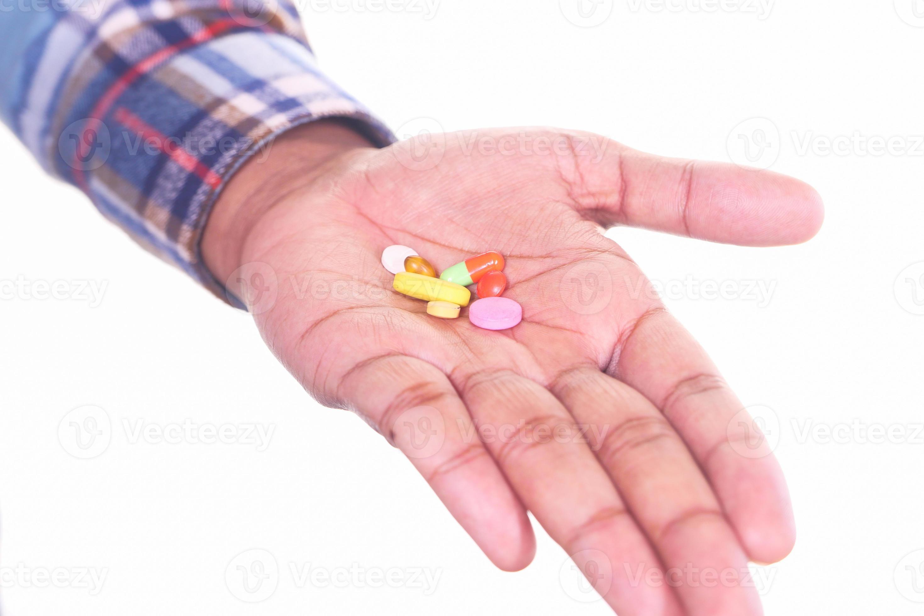 homem segurando comprimidos no fundo branco foto