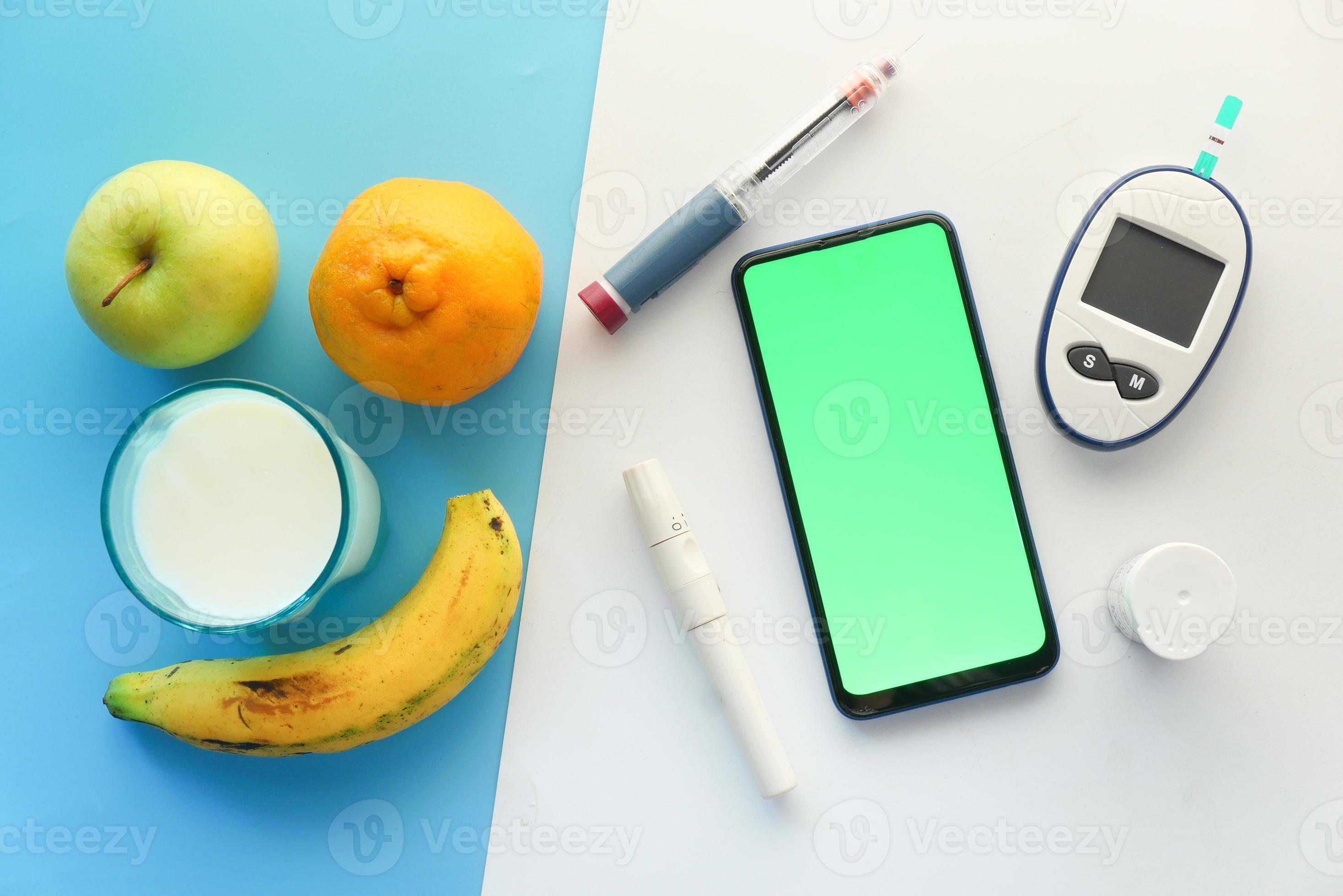 frutas, telefone inteligente e insulina em fundo branco e azul foto