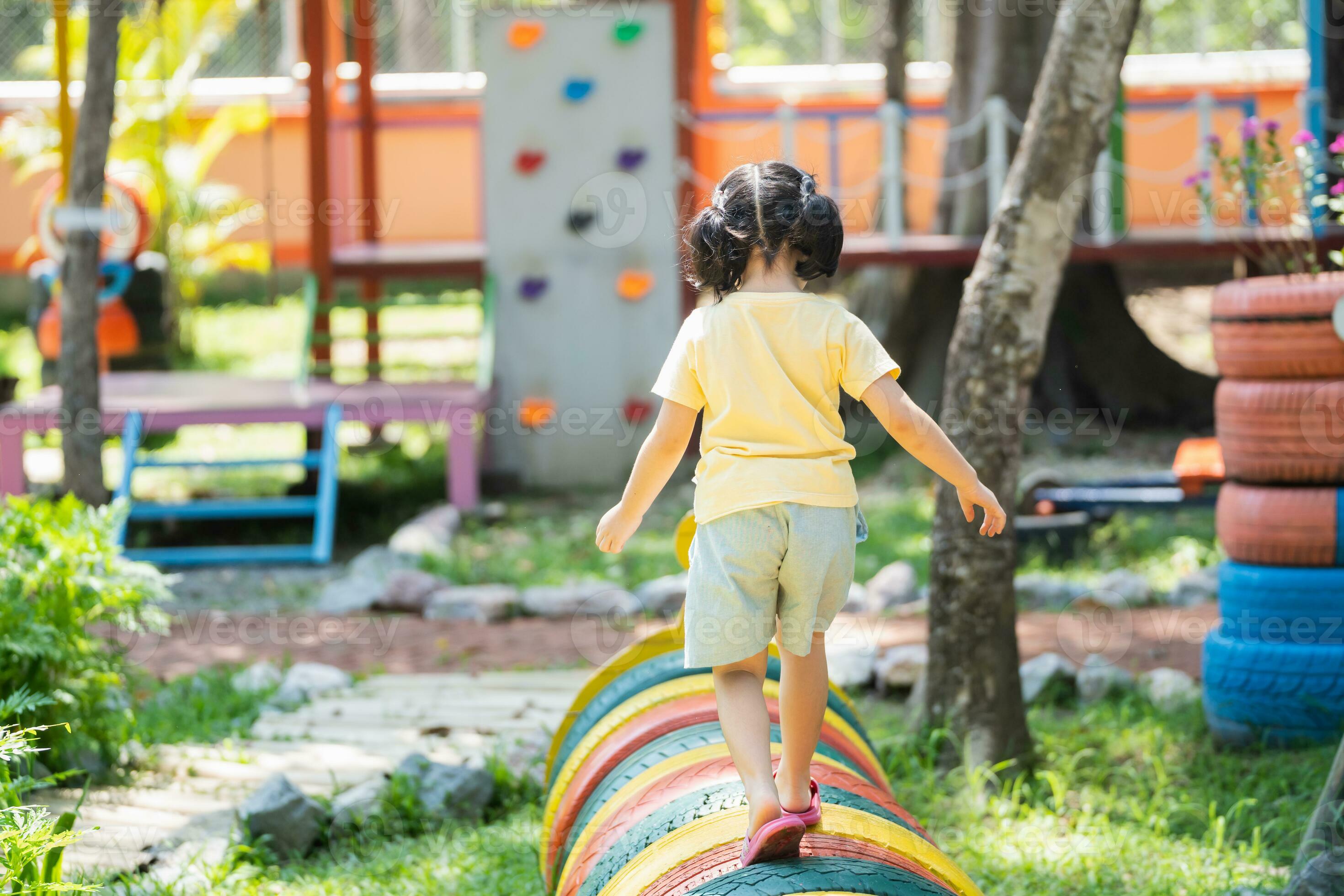 menina asiática bonitinha jogando amarelinha ao ar livre. jogo de atividade  engraçado para crianças no playground