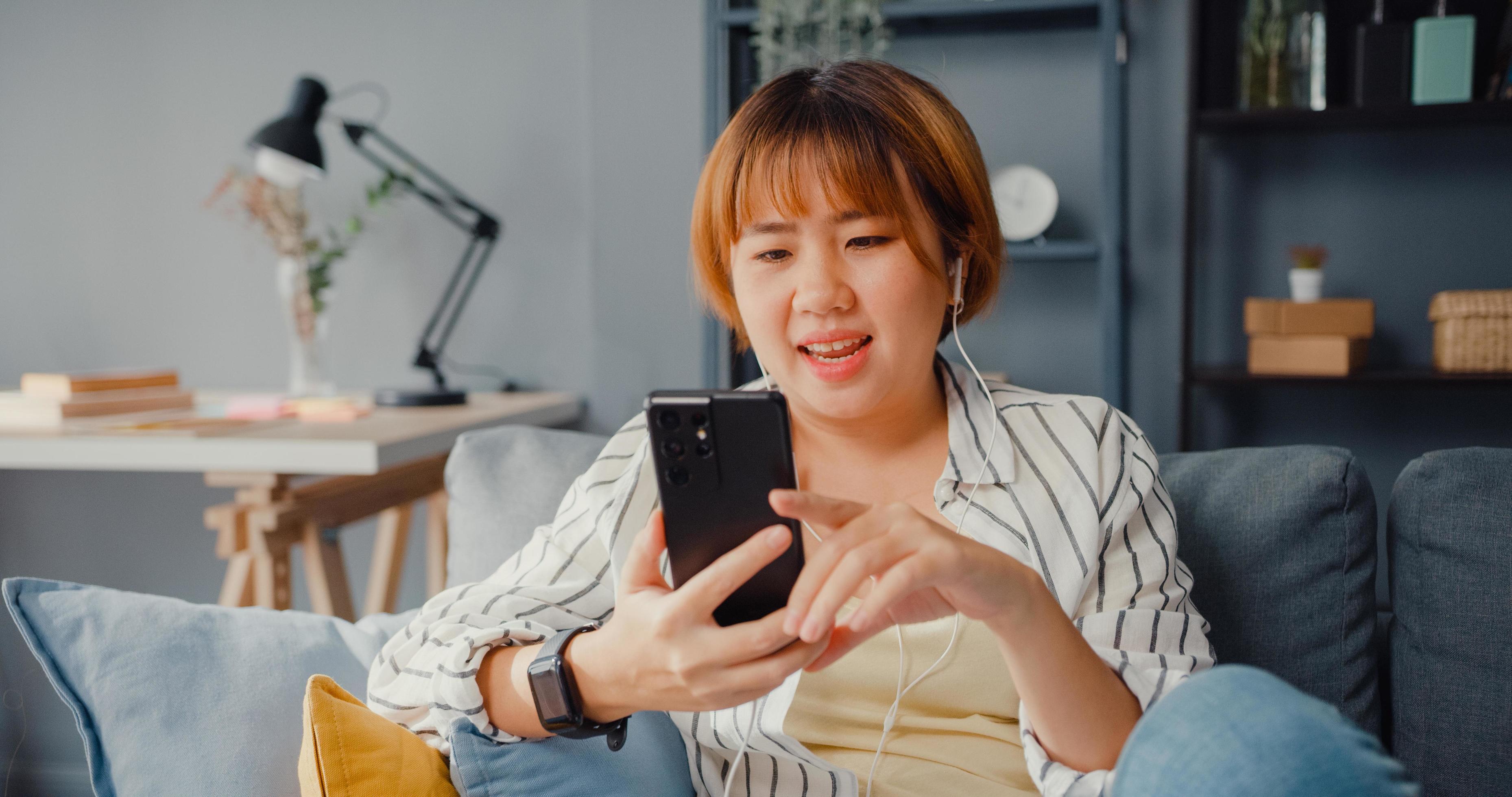 adolescente mulheres asiáticas se sentindo feliz sorrindo relaxe use  videochamada de smartphone na sala de estar em casa. alegre colega de  quarto senhoras videoconferência com amigo e família, mulher de estilo de