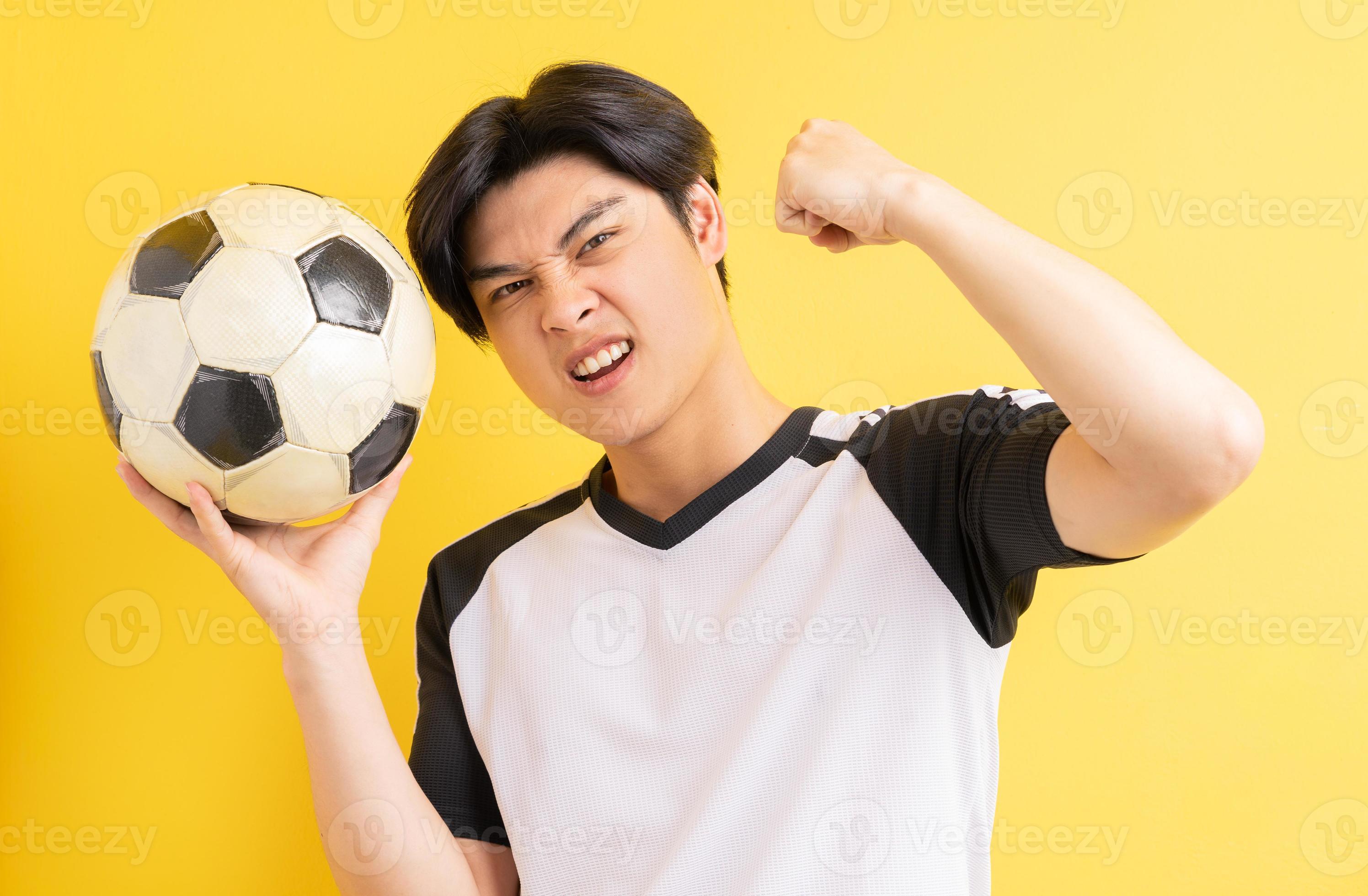 o homem asiático está segurando a bola e mostrando uma expressão triunfante foto