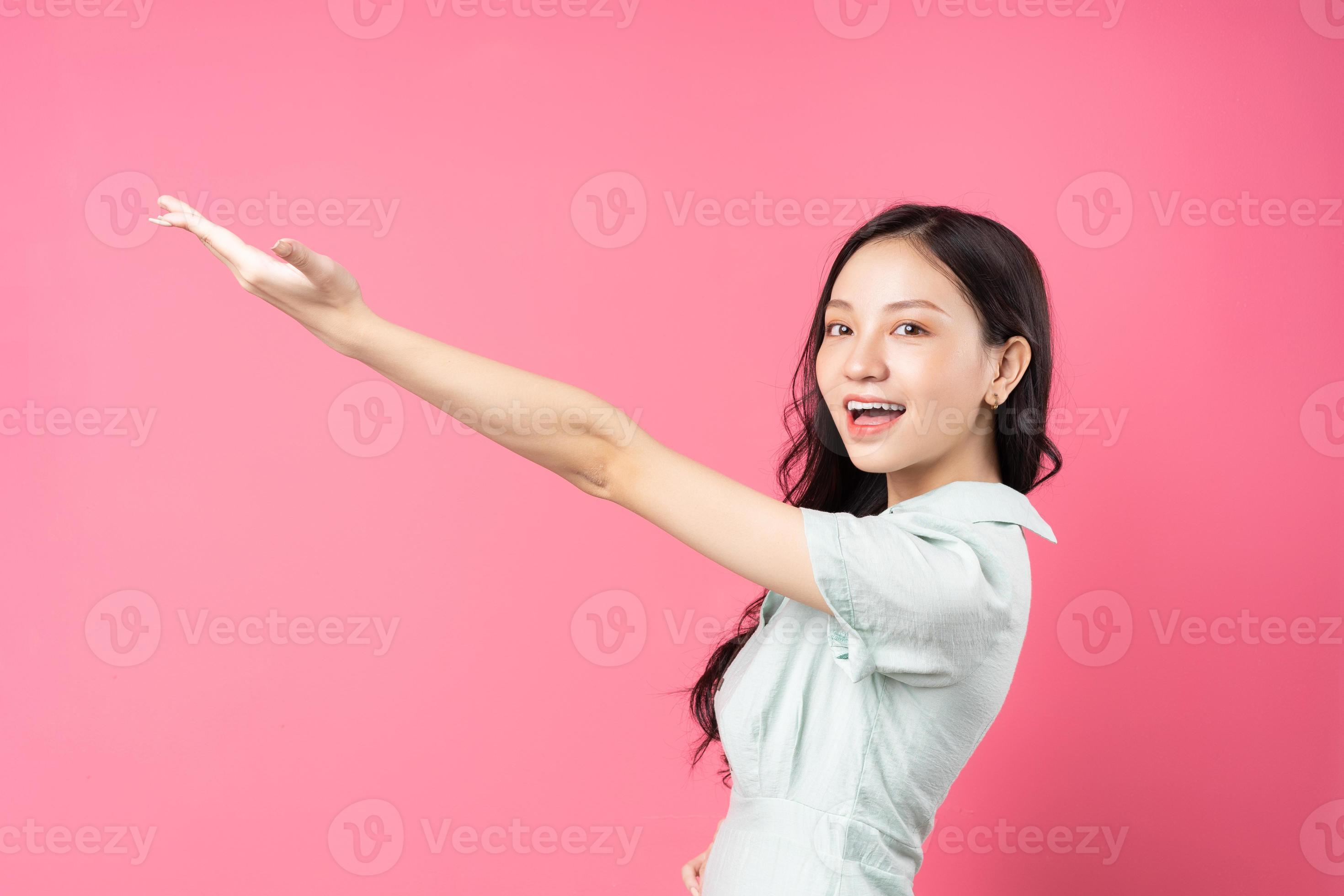 jovem asiática apontando para cima com uma cara alegre foto
