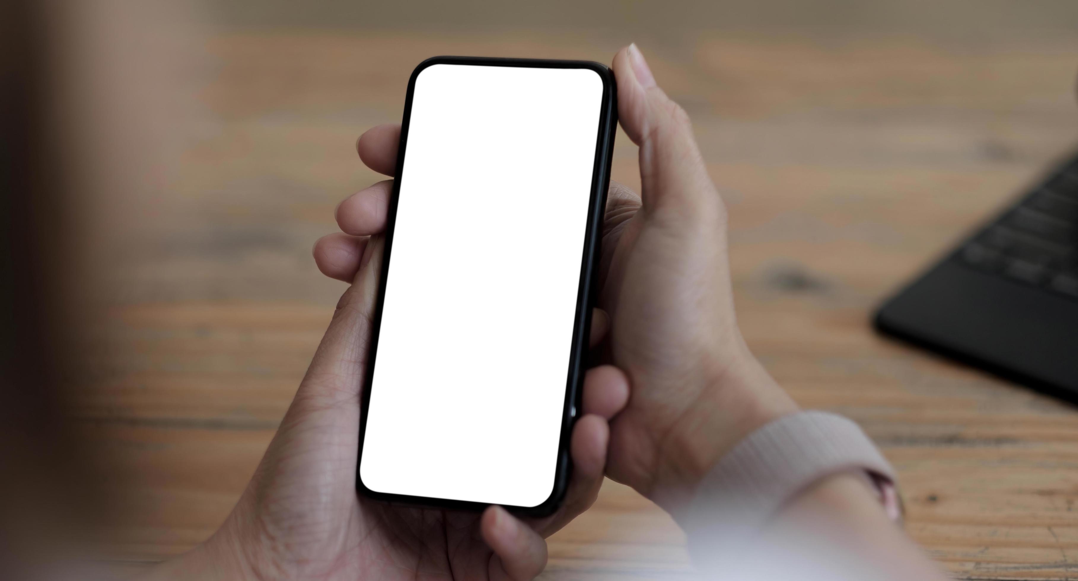 Maquete de telefone celular colocado horizontalmente com tela branca em  branco e fones de ouvido sem fio no fundo de uma velha mesa de madeira  vídeo do jogo aplicativos de áudio podcasts