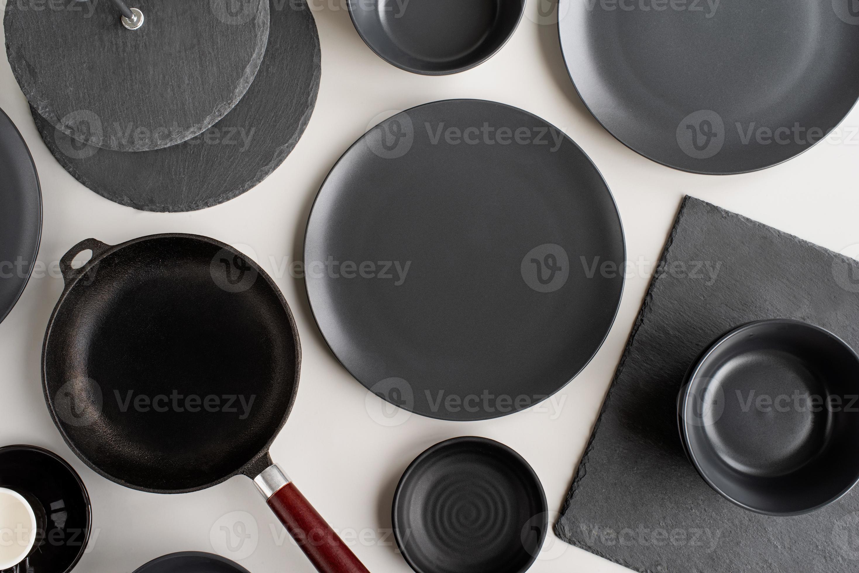pilhas de pratos de cerâmica preta e vista superior de talheres em fundo cinza foto