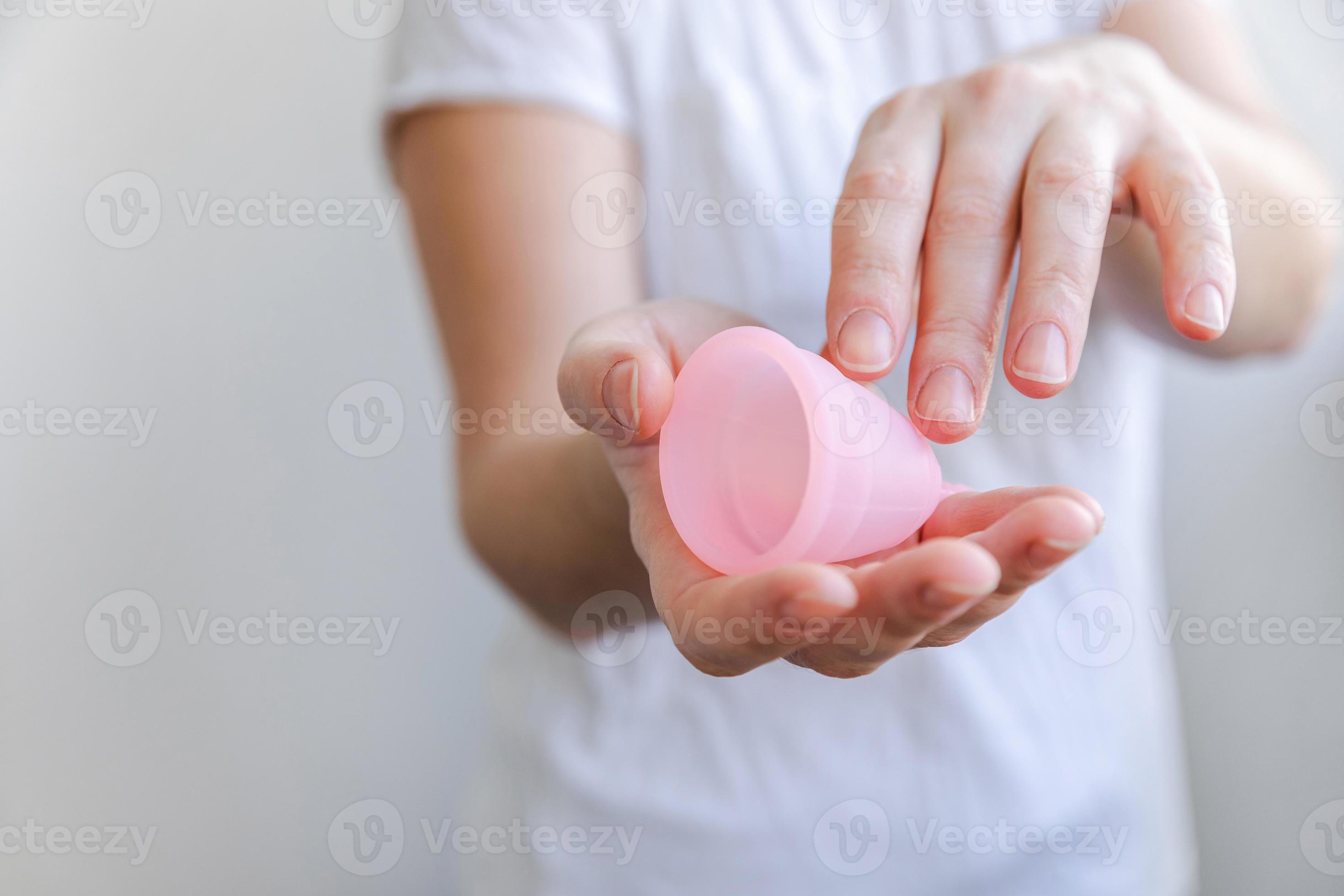 mão de uma mulher segurando o copo menstrual rosa isolado no fundo branco.  mulher moderna alternativa eco ginecológica higiene no período de  menstruação. recipiente para sangue na mão da menina. 5427428 Foto