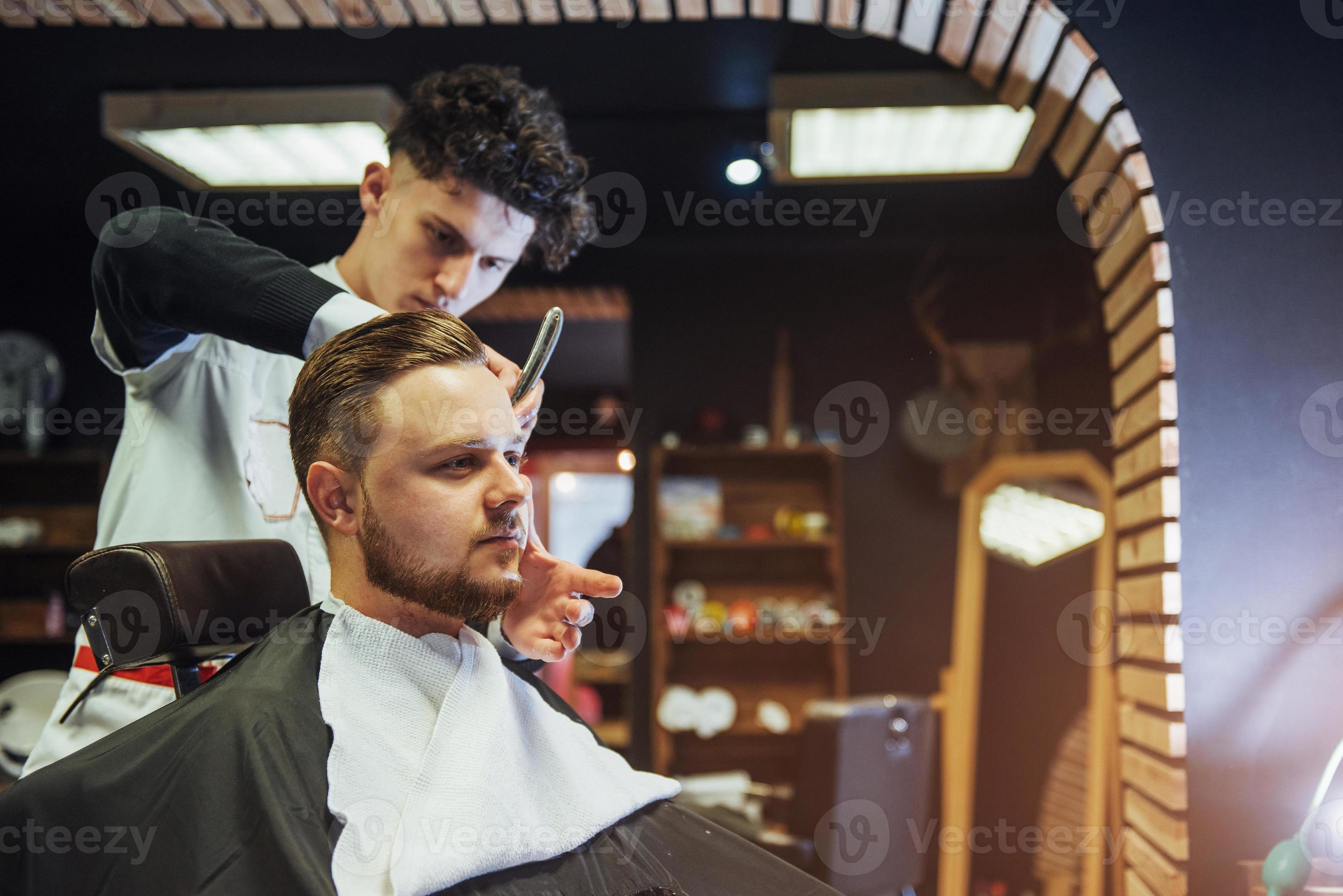 homem cabeleireiro fazendo corte de cabelo barba homens adultos no salão de cabeleireiro masculino foto