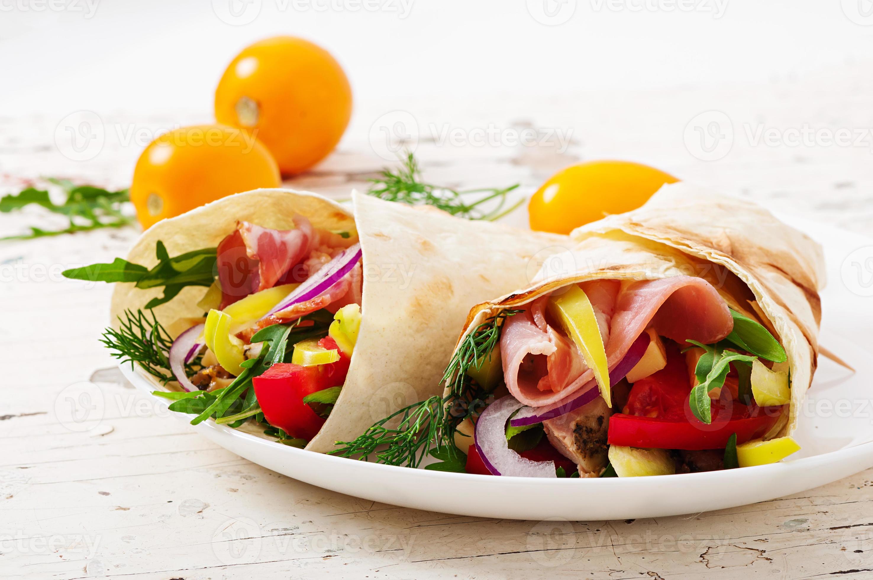 tortilla fresca envolve com carne e legumes no prato foto