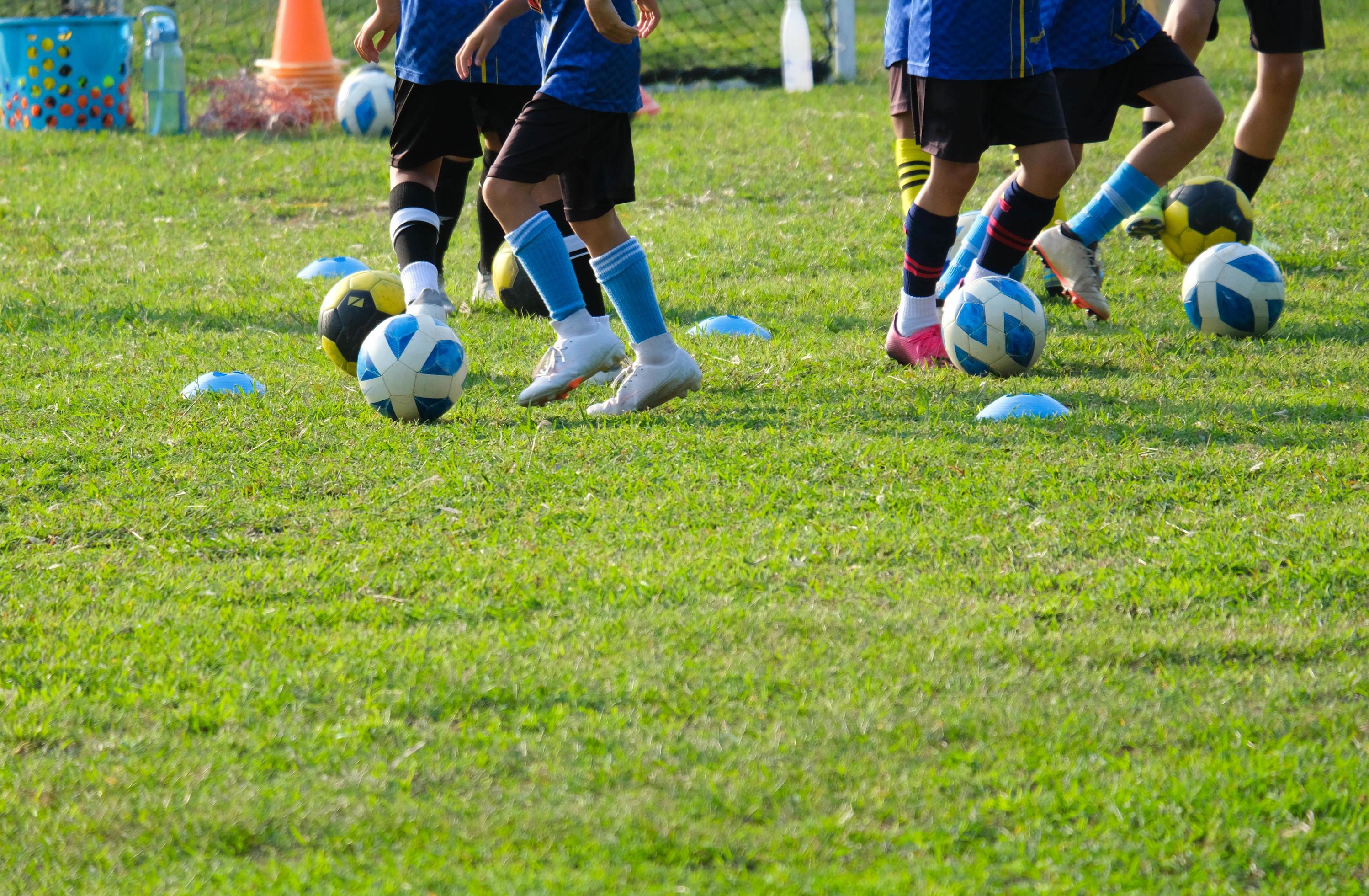 Dois Jogadores De Futebol Chutando Bola De Futebol Em Um Jogo. Meninos Da  Escola Jogam Competição Esportiva. Duas Crianças Multirraciais Jogando  Partida De Futebol. Crianças Em Uniformes De Futebol Verde E Azul