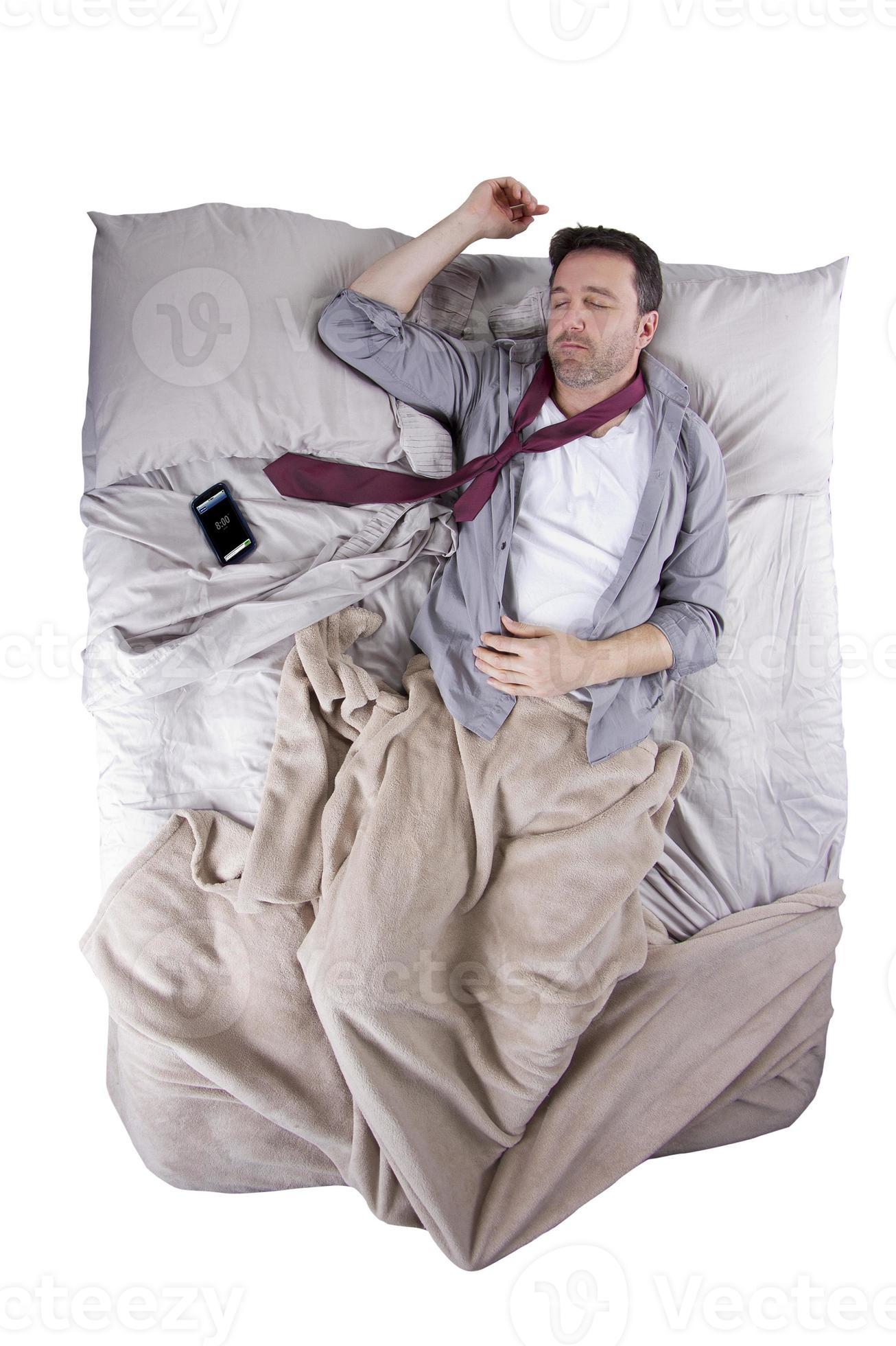 homem caucasiano, dormindo com alarme de celular na cama foto