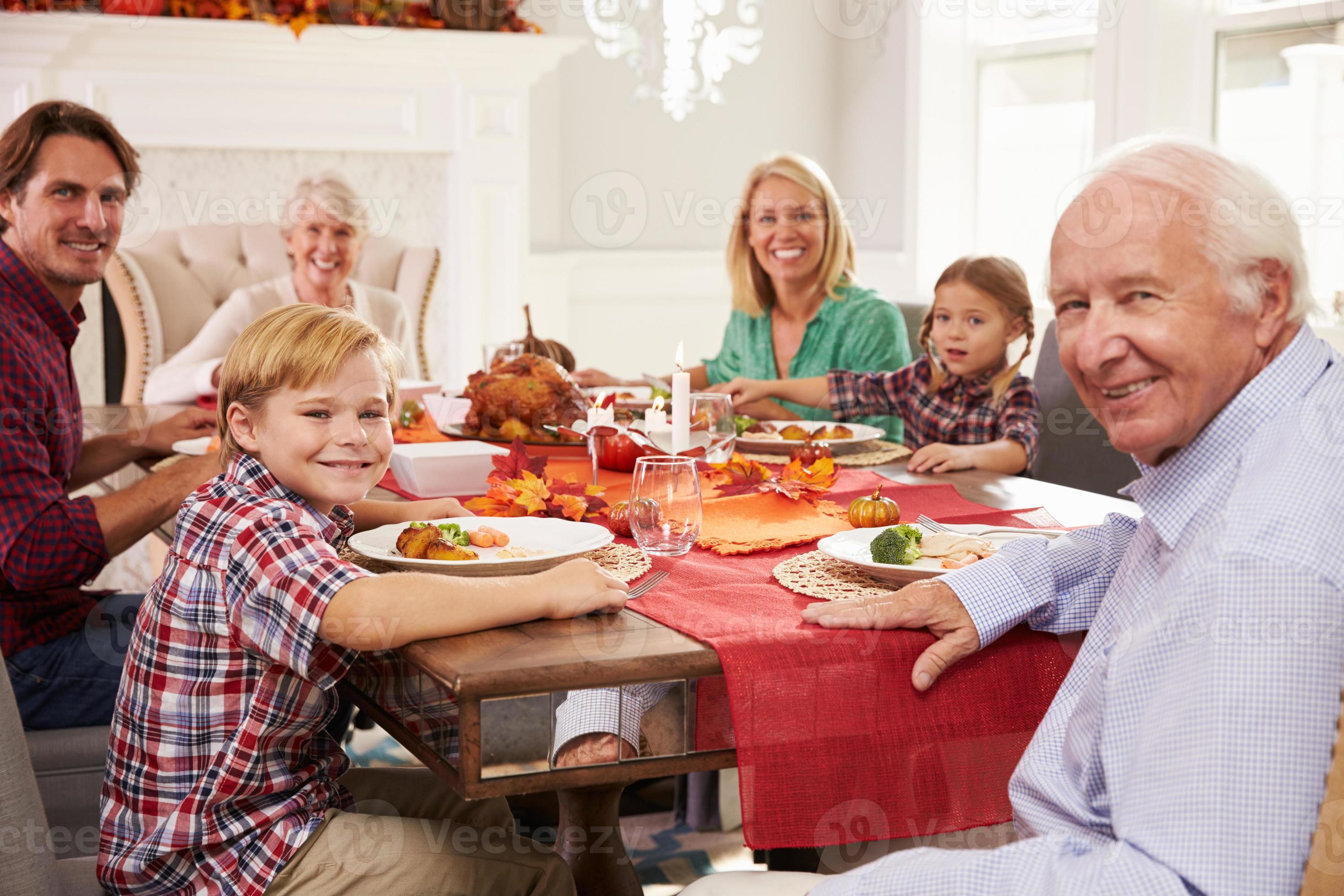 família com avós, aproveitando a refeição de ação de Graças na mesa foto