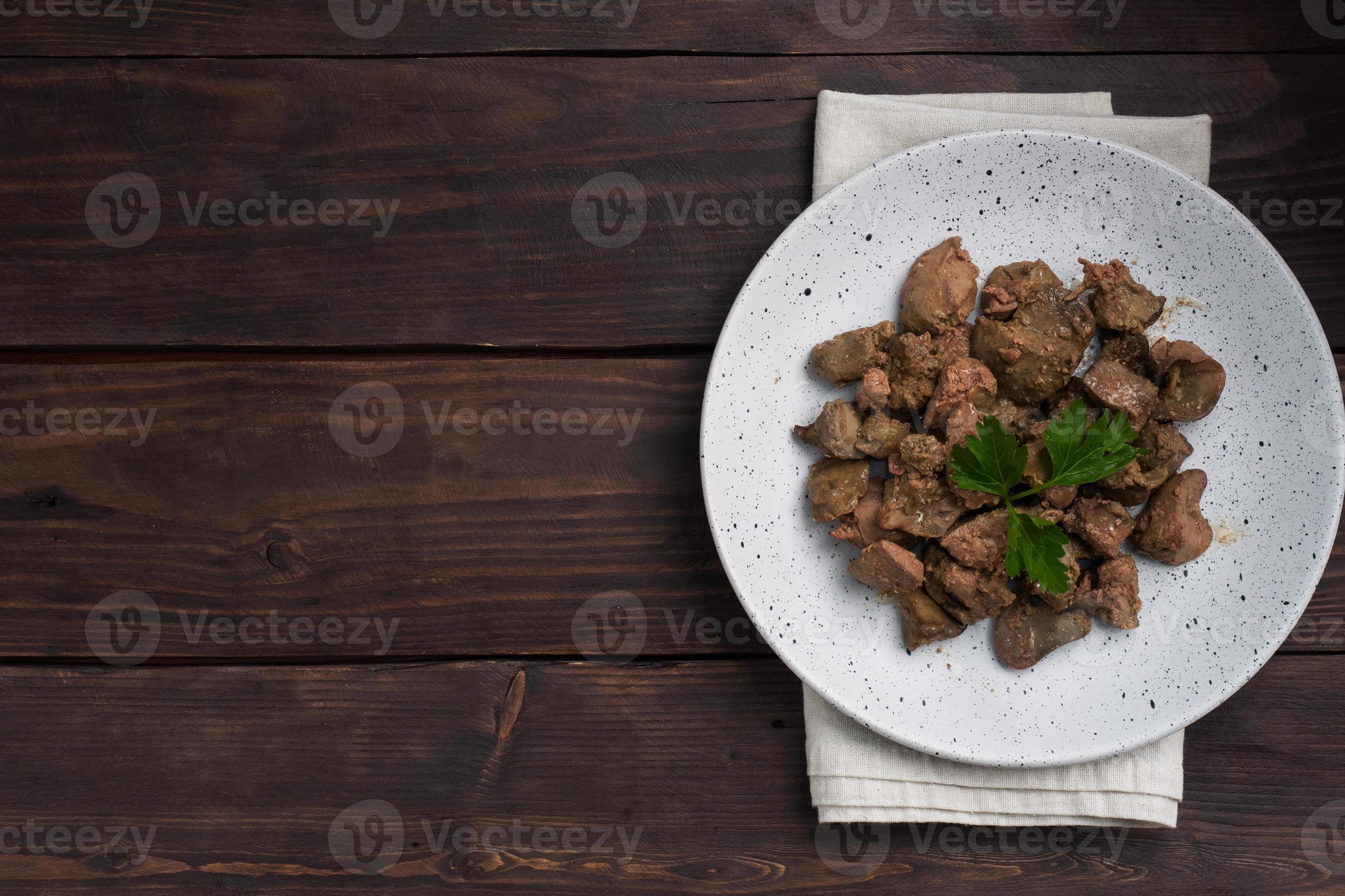 fígado de frango frito ou assado com cebola e molho, folhas de salsa verde  em um prato. prato de carne enriquecido com ferro. espaço de cópia 8957857  Foto de stock no Vecteezy