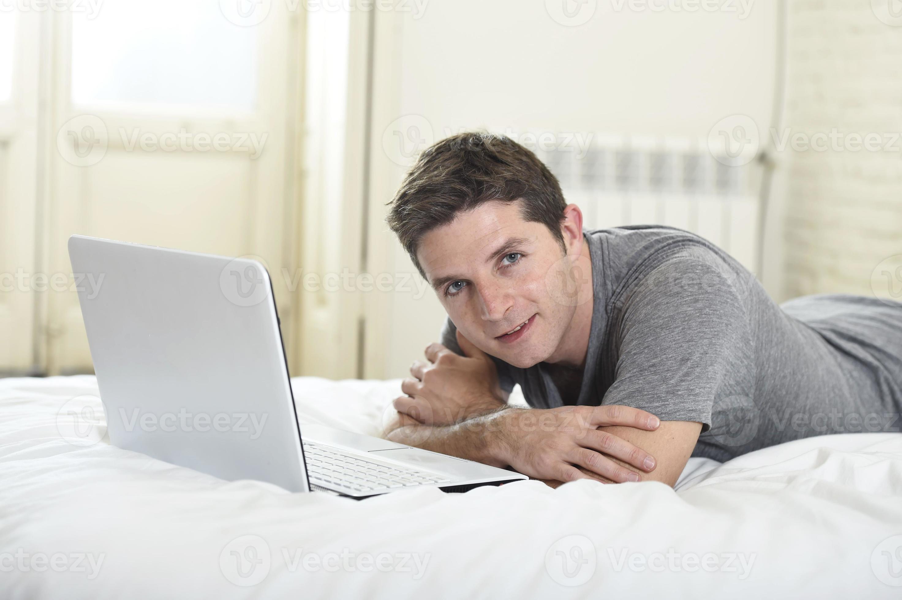 jovem atraente, deitada na cama, desfrutando de computador de rede social foto
