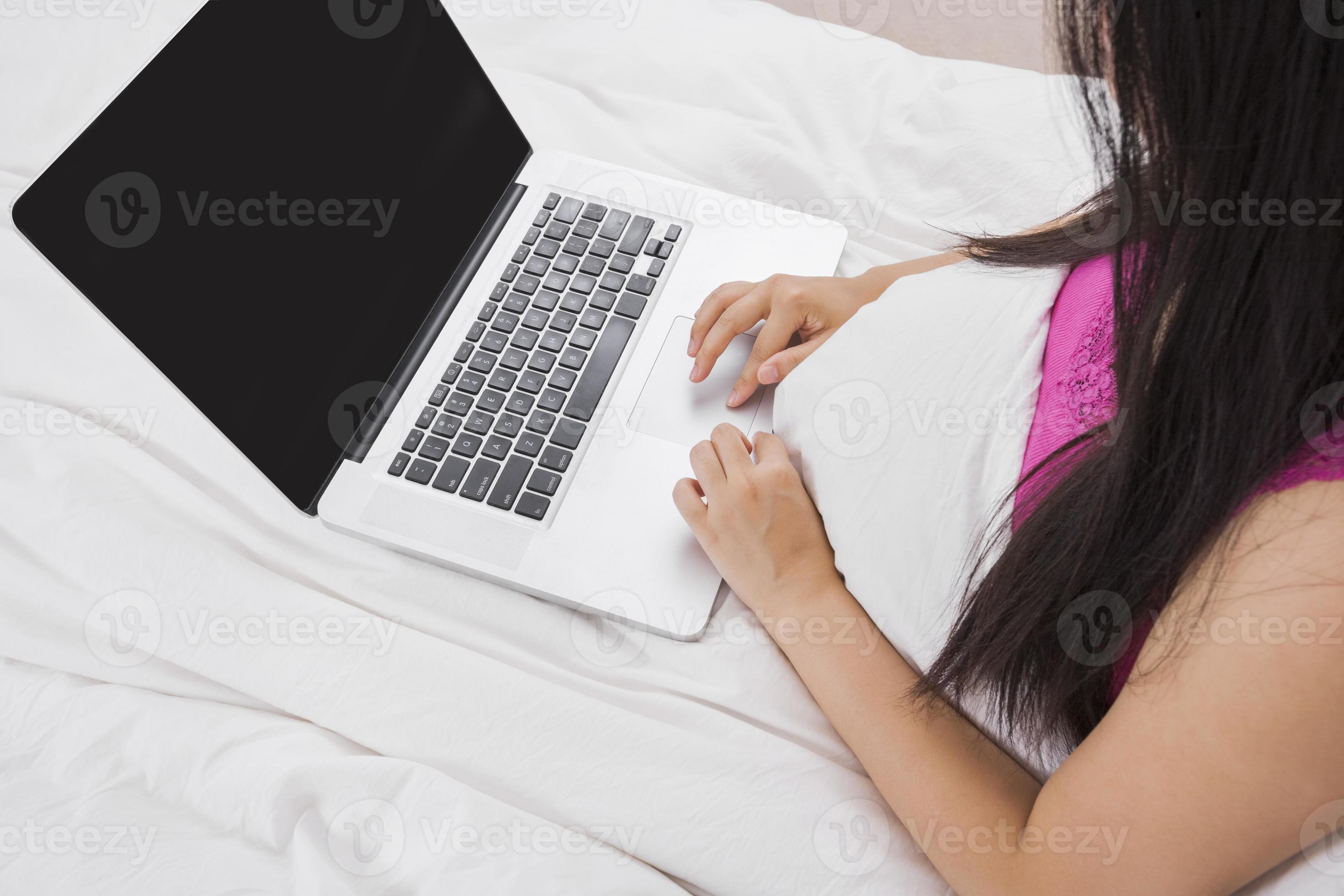 meio de mulher usando o laptop na cama foto