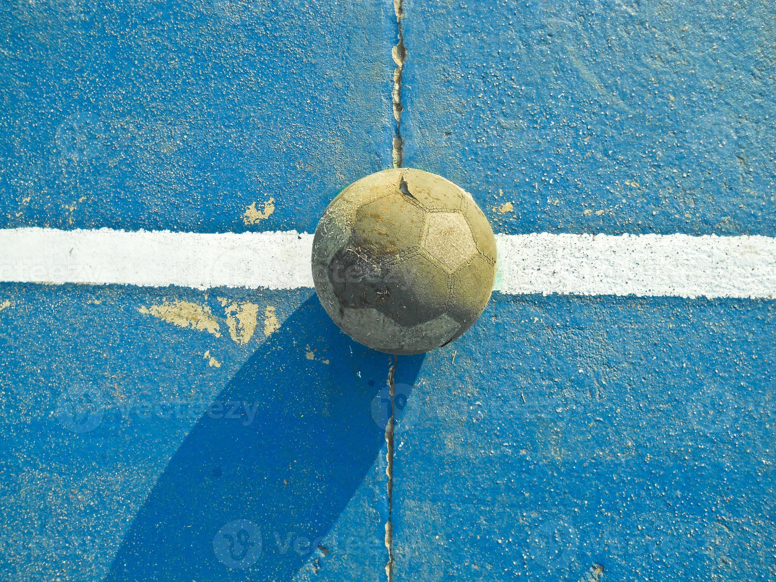 Um garoto segurando a velha bola de futebol antes de começar um jogo de  futebol