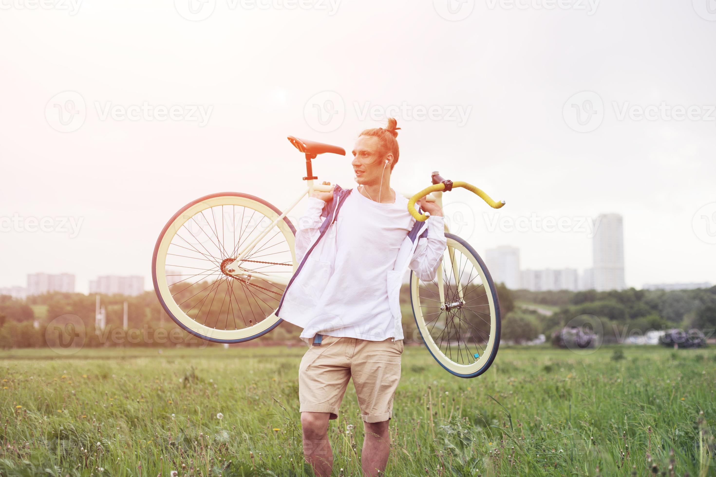 homem sorridente na camiseta em branco andando com bicicleta foto