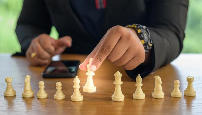 Empresário com as mãos em um terno preto sentado e apontando para o rei do  xadrez na mesa vintage significado de planejamento e estratégia