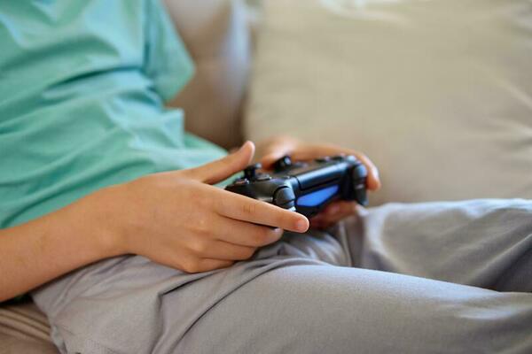 Uma menina sentada no sofá jogando um vídeo na sala de estar em casa. mão  de menina gamer animado segurando o joystick jogando jogo de console usando  um controlador sem fio.