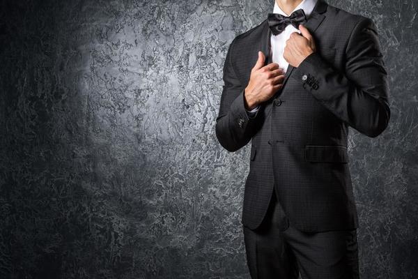 Terno masculino elegante com pôster de gravata borboleta na parede cinza  claro
