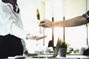 os corretores imobiliários concordam em comprar uma casa e dar as chaves aos clientes nos escritórios de suas agências. acordo de conceito. foto