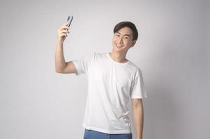 jovem asiático usando smartphone sobre fundo branco, conceito de tecnologia. foto