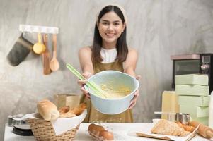 jovem mulher bonita está assando em seu negócio de cozinha, padaria e cafeteria foto