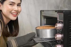 jovem mulher bonita está assando em seu negócio de cozinha, padaria e cafeteria foto