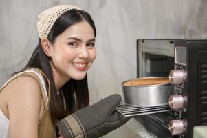 jovem mulher bonita está assando em seu negócio de cozinha, padaria e cafeteria foto