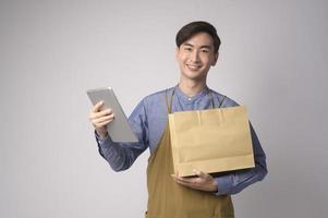 retrato de jovem asiático vestindo avental segurando tablet sobre estúdio de fundo branco, conceito de empresário foto