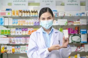 retrato de farmacêutico feminino usando máscara facial em uma farmácia de farmácia moderna. foto