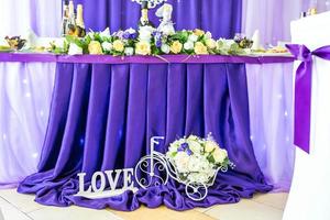 suporte para flores na forma de uma bicicleta e uma inscrição de amor perto da mesa festiva foto