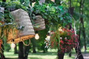 bela decoração de rua com flores, cestas de vime e lâmpadas. lugar calmo e tranquilo aconchegante em um parque. decoração de verão foto