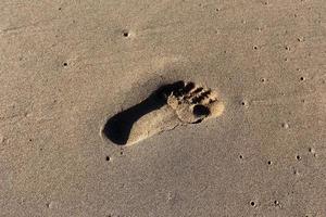 pegadas na areia na praia da cidade. foto