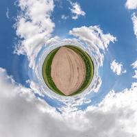 pequena transformação do planeta do panorama esférico 360 graus. vista aérea abstrata esférica na estrada de cascalho entre campo com lindas nuvens impressionantes. curvatura do espaço. foto