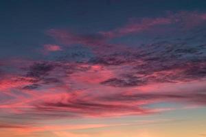 fundo de céu azul violeta vermelho pôr do sol com nuvens de cirrostratus rolando encaracolados fofos à noite. bom tempo ventoso foto