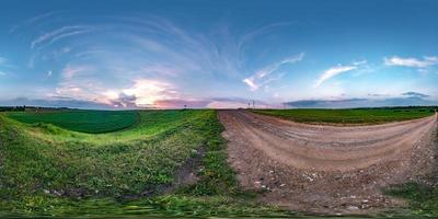 panorama hdri esférico completo sem costura vista de ângulo de 360 graus na estrada de cascalho entre campos no pôr do sol da noite de verão com nuvens impressionantes em projeção equirretangular, conteúdo de realidade virtual vr ar pronto foto