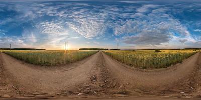 panorama hdri esférico completo sem costura vista de ângulo de 360 graus na estrada de cascalho entre campos no pôr do sol da noite de verão com nuvens impressionantes em projeção equirretangular, conteúdo de realidade virtual vr ar pronto foto