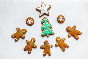 biscoitos de gengibre festivos artesanais em forma de estrelas, flocos de neve, pessoas, meias, funcionários, luvas, árvores de natal, corações para férias de natal e ano novo em fundo de papel branco foto