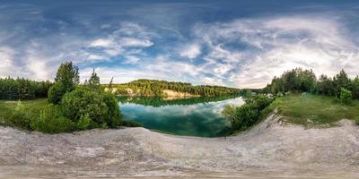 panorama hdri esférico completo sem costura vista de ângulo de 360 graus na costa de calcário do enorme lago verde ou rio perto da floresta em dia de verão com belas nuvens em projeção equirretangular, conteúdo vr foto