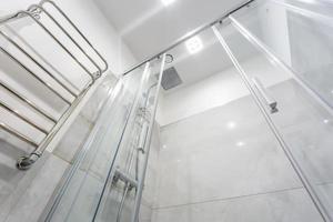 detalhes da cabine de chuveiro de canto com acessório de chuveiro de parede e pia de torneira de água com torneira no banheiro caro foto