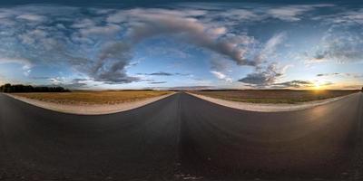 panorama esférico completo sem costura vista de ângulo de 360 graus na estrada de asfalto entre campos no pôr do sol da noite de verão com nuvens impressionantes em projeção equirretangular, skybox vr ar conteúdo de realidade virtual foto