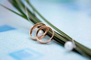 os anéis dos noivos ficam perto do caule das flores do buquê de casamento foto