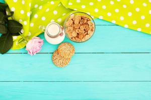 flocos de aveia e biscoitos com jarro de leite na cozinha de madeira azul. toalha de mesa em bolinhas, rosa. foco seletivo foto