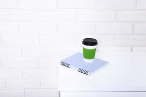 elegante macro xícara de café e notebook no escritório. foco seletivo e espaço de cópia. parede de tijolos e conceito de negócio no local de trabalho. foto